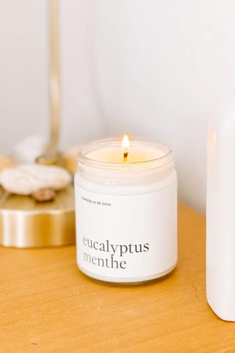 Chandelle de soya eucalyptus et menthe allumée dans un pot de verre , posée dans un décor épuré, diffusant un parfum frais et revigorant.