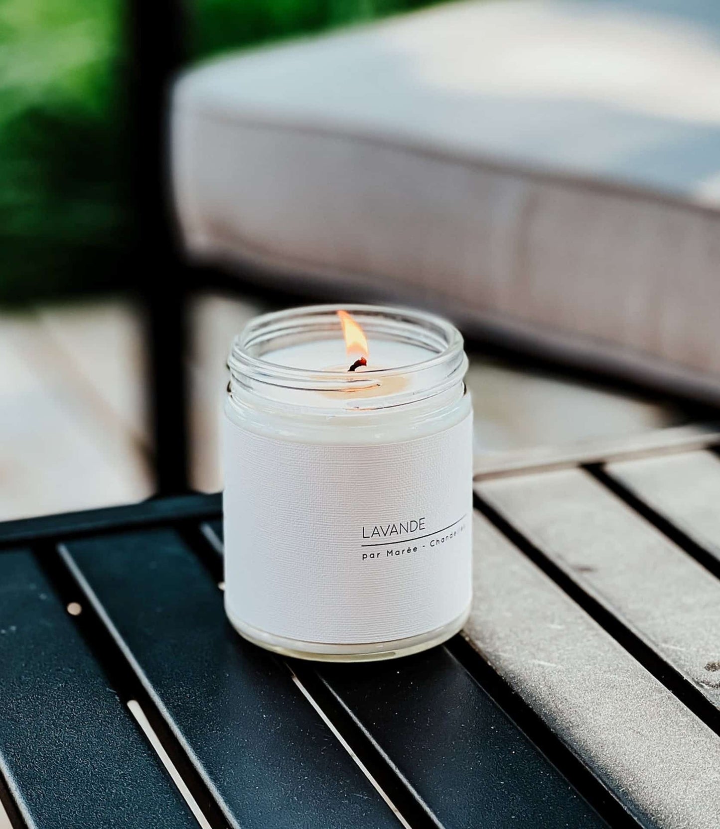 Chandelle de soya à l’huile essentielle de lavande allumée sur une terrasse en bois, diffusant un parfum naturel et apaisant pour éloigner les moustiques.