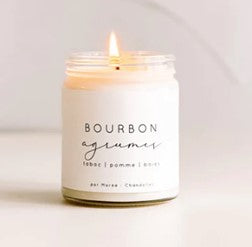 Chandelle de soya Bourbon Agrumes allumée dans un pot en verre , posée sur une surface blanche – flamme douce diffusant un parfum d’agrumes frais, de vanille sucrée et de bourbon boisé.