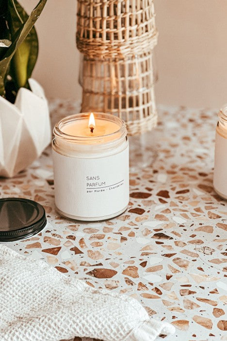 Chandelle de soya sans parfum Marée allumée, dans un pot en verre, posée sur un comptoir dans un décor rustique – lumière douce et ambiance naturelle sans odeur.