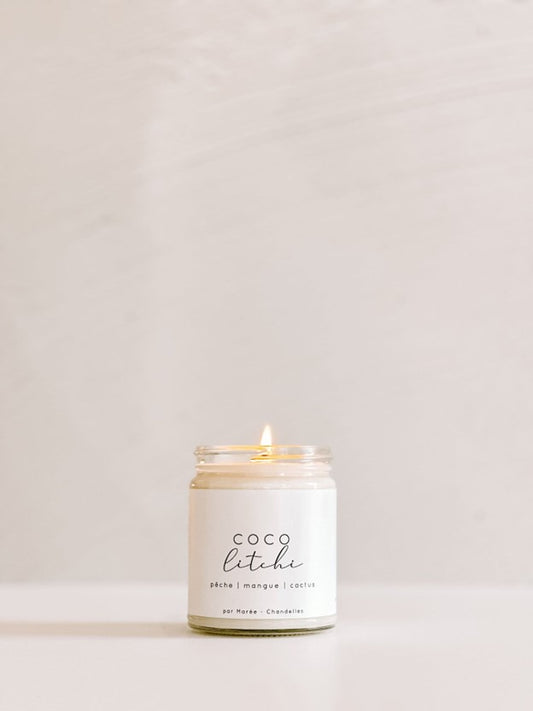 Chandelle de soya Coco Litchi allumée dans un pot en verre ,posée dans un décor lumineux – flamme douce diffusant un parfum de noix de coco, litchi et fruits exotiques.

