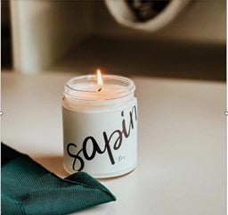 Chandelle de soya Sapin allumée dans un pot en verre  diffusant une fragrance boisée de conifère, parfaite pour recréer l’ambiance chaleureuse de Noël.