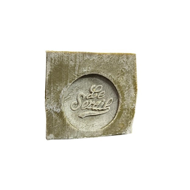 Bloc de savon de Marseille vert, estampillé 72% huile d’olive, posé sur une surface neutre.