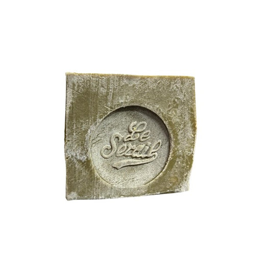 Bloc de savon de Marseille vert, estampillé 72% huile d’olive, posé sur une surface neutre.